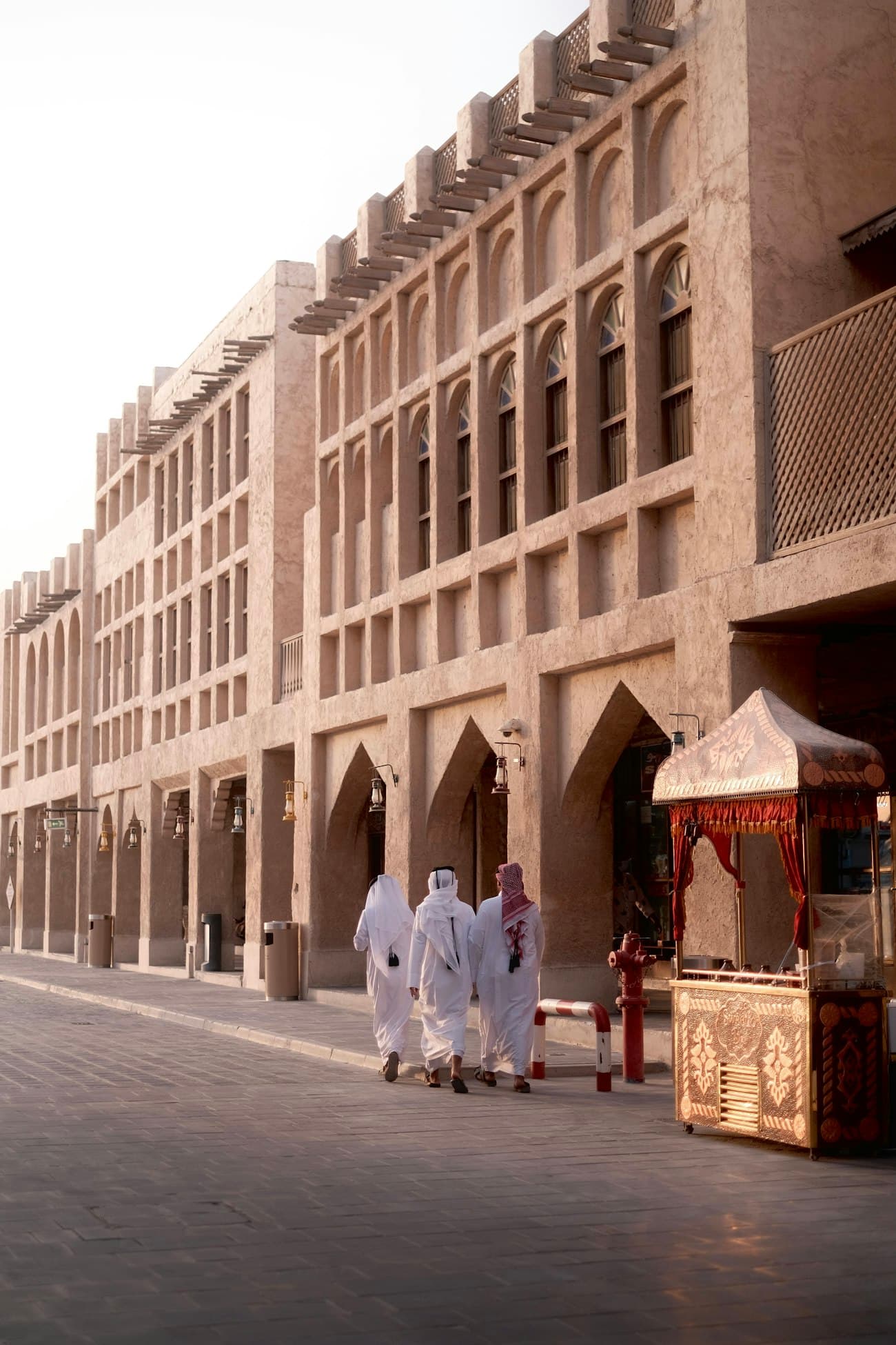 رجالٌ بالزي القطري يمشون في ممرّ سوق واقف بالدوحة